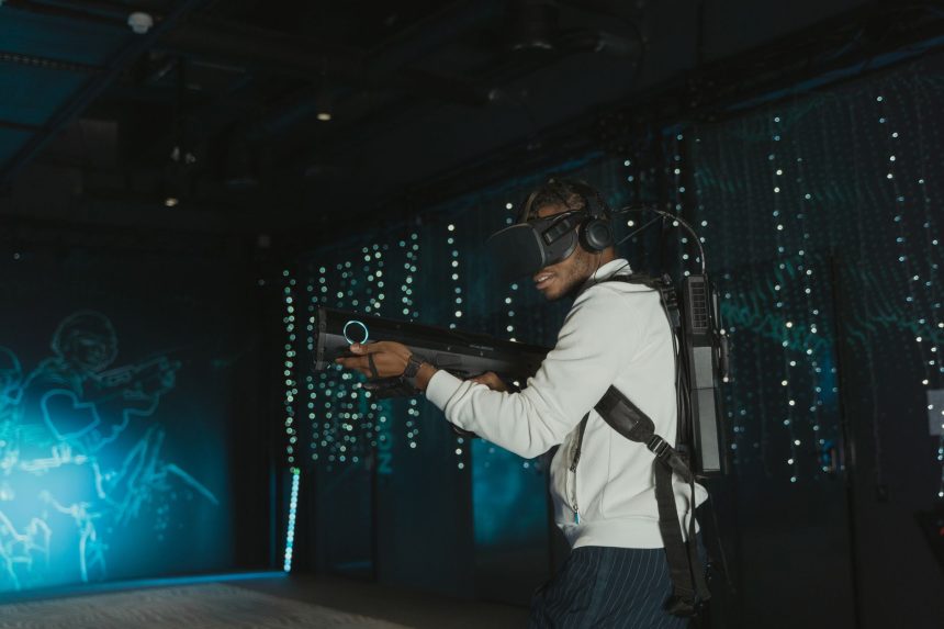 Homem usando um headset de realidade virtual e uma arma simulada durante uma partida de videogame.