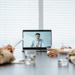 Equipe diversa participa de uma reunião virtual usando recursos digitais em um ambiente corporativo.