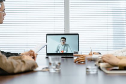 Equipe diversa participa de uma reunião virtual usando recursos digitais em um ambiente corporativo.
