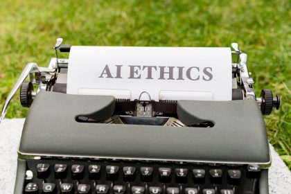Máquina de escrever ao ar livre com uma folha exibindo as palavras “AI ethics”.